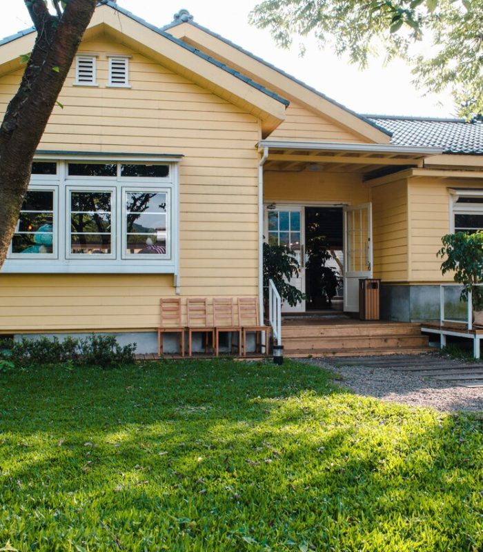 charming-yellow-house-with-wooden-windows-green-grassy-garden_181624-8074