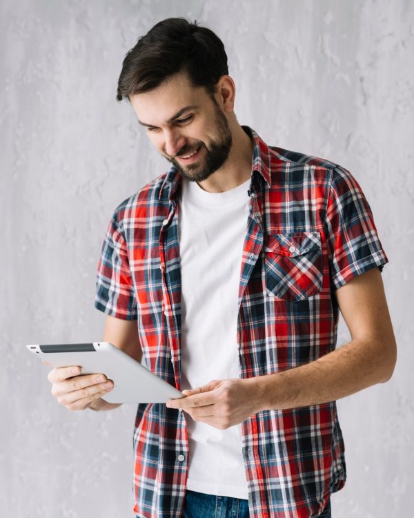 cheerful-man-using-tablet-near-wall_23-2147800068